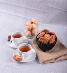 Two cups of tea with biscuit and chocolate