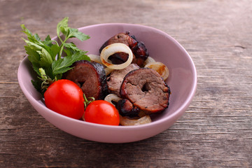 Grilled meat pieces in a plate on a dark background