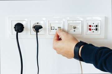 Male hand puts network plug in the socket