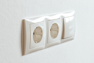 A group of white european electrical outlets and a switch located on a white wall