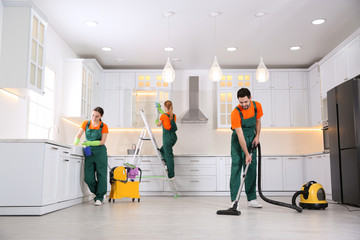 Team of professional janitors cleaning modern kitchen