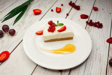 Appetizing sweet dessert on a white plate. A restaurant dish on the table decorated with strawberries and grapes.