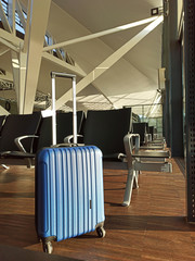 Blue suitcase in an empty airport. Waiting area Flight delay cancellation. Travel and vacation concept. Coronavirus COVID19 quarantine