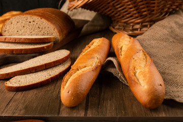 Slices of brown and white bread on kitchen board with baguette