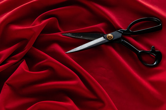 Red Fabric On The Table With Black Professional Scissors, Cutting Fabric