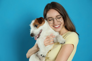 Young woman with her cute Jack Russell Terrier on light blue background. Lovely pet