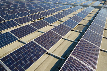 Aerial view of many photo voltaic solar panels mounted of industrial building roof.