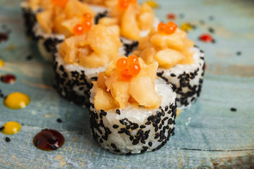 A close up of fresh rolls, fish, caviar and black sesame seeds, served on a blue plate