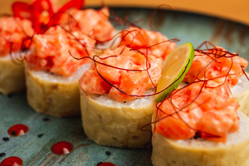 A close up of fresh maki with fish on top, served on a blue plate