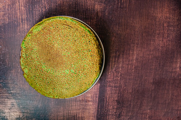 Pancakes with spinach on dark brown wooden table. Top view. Copy space.