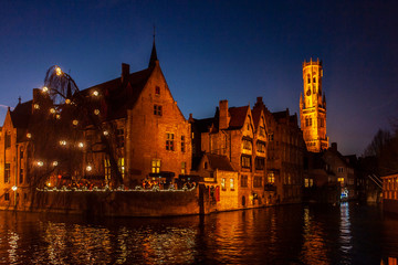 Brujas de noche con una de sus torres medievales y un canal en primer plano