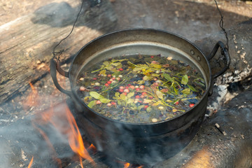 Fototapeta na wymiar A pot with a herbal tea on campfire