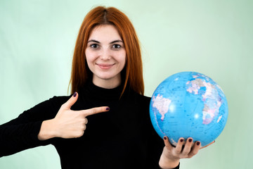 Portrait of a happy young woman holding geographic globe of the world in her hands. Travel destination and planet protection concept.