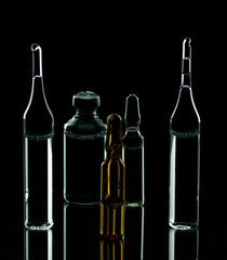 Glass ampoules with liquid on a black background. Medical items. Virus. Prevention and treatment.