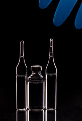 Ampules for injection, medical gloves on a black background.