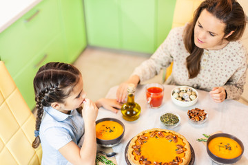 Autumn family dinner. Family: mom and daughters laid all the pumpkins on the table. Dining party, pumpkin dinner: orange soup, pumpkin pie decorated with pecans on a served table and other dishes