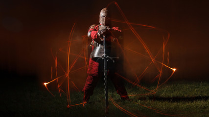 Medieval knight in the armor with the sword, Magic fire lines around him.