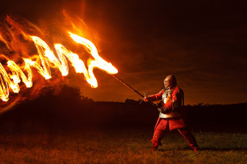 Medieval knight in the armor with the sword fights with the fire dragon.