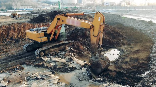 Excavator cleaning quarry. Construction equipment, heavy industry machinery.