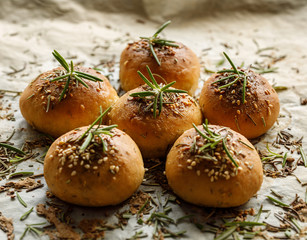 Homemade baked rosemary rolls on baking parchment close up