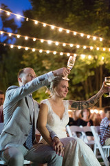 Bride and groom toasting with flutes in outdoor wedding reception