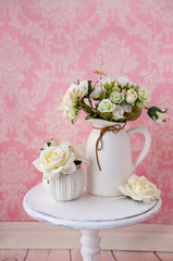 Fabric flowers on a vintage table on a pink background with a vintage pattern.