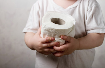 A roll of toilet paper in the hands of a child.