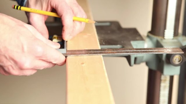 Drawing a pencil line on wood with a square.