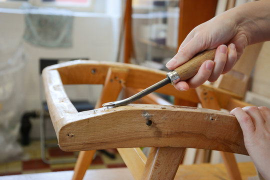 Woman hands in upholstery workshop. Removing old tacks. Working with upholstery tools. Nail remover. Tack lifter removing old nails from wooden construction.