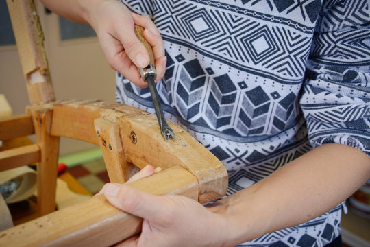 Woman hands in upholstery workshop. Removing old tacks. Working with upholstery tools. Nail remover. Tack lifter removing old nails from wooden construction.
