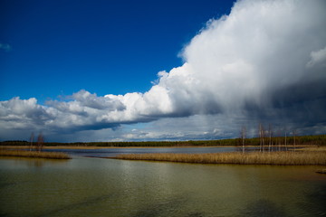 Belated snow charge over a forest lake on a fine spring day, Central Russia.