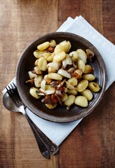  Gnocchi with onion and mushrooms. Rustic wooden background. Top view.