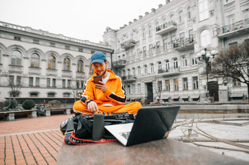 DJ sitting with a controller and a laptop on the street, playing music on an Audio mixing...