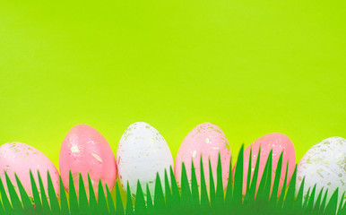 Concept of spring and Happy Easter pink and white with gold eggs on a colorful yellow bright background, grass cut out of paper