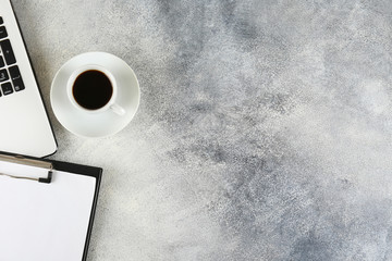 Cropped shot of black and white laptop keyboard with stationery accessories. Workspace of designer concept. Grunged stone background. Top view, flat lay, copy space.