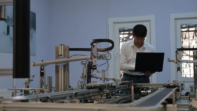 Industry 4.0 concept; Engineer is working on laptop to program smart factory prototype's automation. automated car on production line, artificial intelligence in smart manufacturing.
