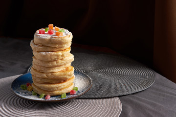stack of pancakes powdered with sugar powder and decorated with dried fruit
