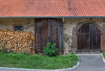 Altes landwirtschaftliches Gebäude mit Holzstoß und zwei Toren