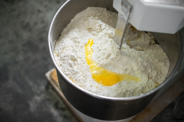 Woman mixing dough with professional kneader machine at the manufacturing
