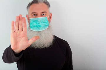 Portrait of middle-aged bearded man in a medical mask. A concept of the danger of coronavirus for the elderly.