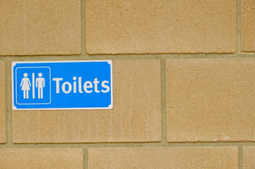 Obraz premium Public toilet sign for restroom with man and woman picture in blue color on a brick wall background