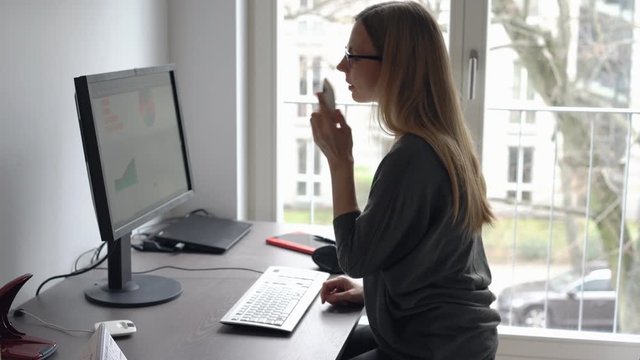 Frau im Homeoffice telefoniert und arbeitet am Computer