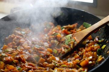 Stir- fry vegetables and portobello mushrooms in a wok. Selective focus.