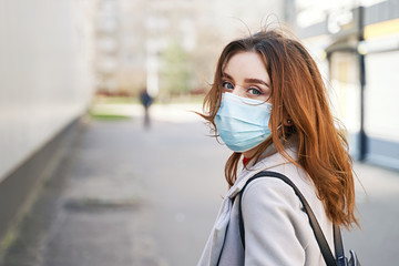 Young woman with beautiful blue eyes and disheveled hair wearing protection face mask against...