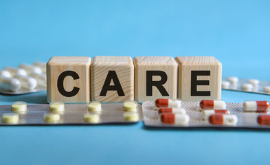 CARE - text on cubes. Drug, tablets in blisters to reduce disease symptoms
