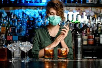 bartender girl in medical mask at bar counter.