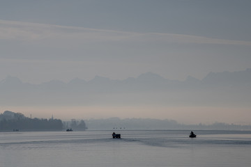 fisherboat in the morning with alps panorama in background monochron and quiet sunrise scenery