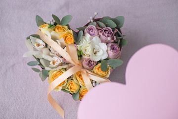 Stylish flowers arrangement in a pink hatbox. White orchid, purple and yellow roses with bunch. Birthday present. Flowers bouquet on background whith copy spase. Romantic concept