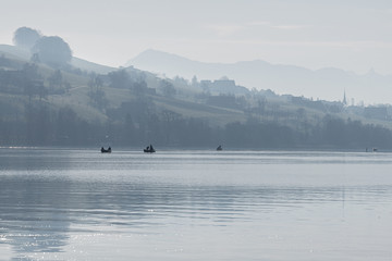 fisherboat in the morning with alps panorama in background monochron and quiet sunrise scenery