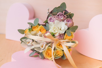 Stylish flowers arrangement in a pink hatbox. White orchid, purple and yellow roses with bunch. Birthday present. Flowers bouquet on background whith copy spase. Romantic concept